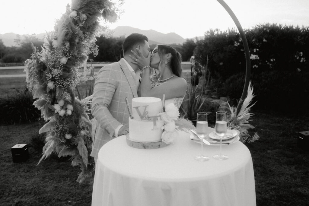 Brautpaar hat die Hochzeitstorte angeschnitten und küsst sich jetzt.