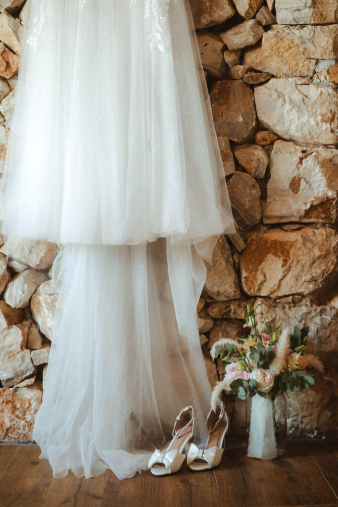 Foto vom Brautkleid mit Brautstrauß und Brautschuehen.
