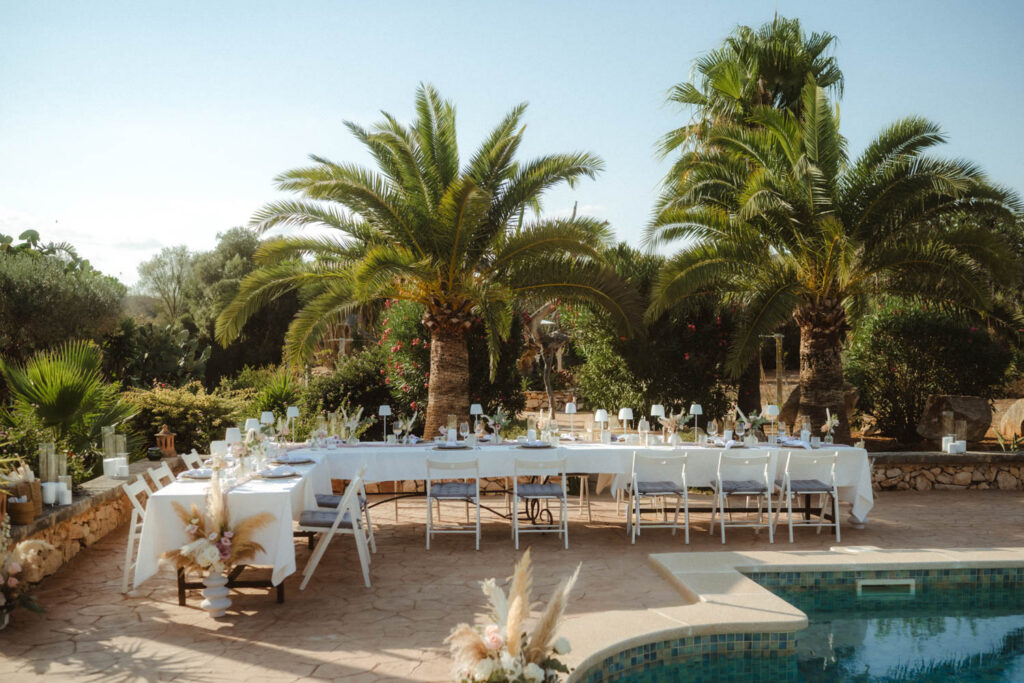 Foto vom Dinnertisch auf einer Hochzeit auf Mallorca. Tisch steht neben dem Pool und vor Palmen.